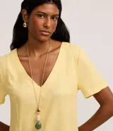 Vestido corto amarillo de viscolino, con escote en V, mangas cortas y bolsillos frontales aplicados.