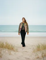 Campera bomber con diseño de paneles combinados: mangas y espalda en color verde oliva acolchado, y frente con paneles laterales estampados en tonos tierra y violeta. Presenta cuello, puños y ruedo en tejido de punto acanalado color marrón, con cierre frontal completo.