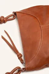 Cartera bandolera de cuero marrón con forma relajada, diseño de costuras curvas y detalles de nudos hechos a mano en las asas.