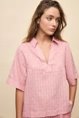 Blusa celeste de manga corta con cuello camisero y escote en V, confeccionada en tejido liviano con textura sutil y estampado de lunares.