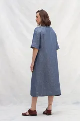 Vestido camisero midi de lino color celeste, con abotonadura frontal completa, manga corta ranglan, bolsillos laterales y volante en el ruedo.
