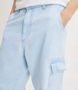 Pantalón de jean modelo baggy con bolsillos cargo laterales, cintura con trabillas y cierre frontal con botón y cremallera.