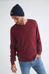 Sweater de tejido de punto color beige, con escote en V, mangas largas y puños y dobladillo acanalados. Presenta un pequeño logo bordado en el pecho.