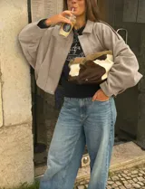 Chaqueta tipo bomber de calce holgado, confeccionada en gamuza color beige. Presenta cuello camisero, cierre frontal, mangas amplias y largo a la cintura.