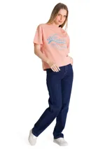 Remera de corte boxy y relajado, color rosado, con cuello redondo y mangas cortas. Presenta un estampado gráfico frontal de estilo retro con tipografía en tonos azules y rojos.