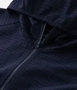 Chaqueta deportiva masculina de color azul marino, confeccionada en tejido técnico repelente al agua con acabado texturizado. Presenta cierre frontal con cremallera, capucha integrada y estampado de coordenadas en el pecho.