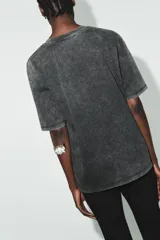 Camiseta de algodón con efecto lavado, cuello redondo y manga corta. Presenta un acabado con sutiles brillos integrados en el tejido y un corte regular.
