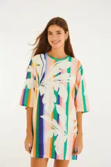 Vestido corto estilo remerón de algodón, con estampado de rayas verticales multicolor y grandes hojas tropicales en el frente. Tiene cuello redondo, hombros caídos y mangas amplias hasta el codo.