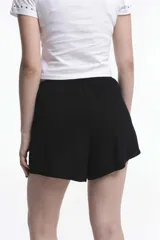 Short pollera de viscosa con estampado floreado sobre base rosada, diseño cruzado estilo pareo con nudo lateral y cintura elástica.