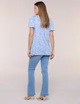 Blusa estampada en tonos de azul y blanco, con escote redondo, aplique artesanal bordado en el centro del pecho, mangas cortas tipo mariposa con volados y ruedo asimétrico.