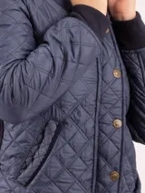 Campera negra capitoneada con paneles laterales acanalados, cuello alto y cierre con botones a presión.