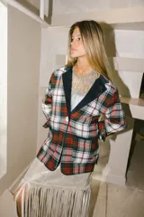 Blazer de paño de lana con estampado a cuadros en tonos rojo, blanco y negro. Tiene solapa en pana azul marino y corte recto.