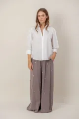 Pantalón de corte ancho y tiro alto, color gris topo, confeccionado en tencel con detalle de pequeñas aplicaciones de strass distribuidas por toda la prenda.