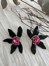 Par de aros colgantes con forma de flor negra y centro de cristal rosa rodeado de strass.