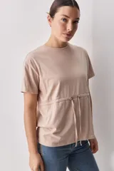 Remera de algodón color rosado, de corte relajado, con cuello redondo, mangas cortas y detalle de cordón regulable en la cintura.