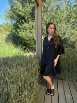 Vestido corto de lino color beige claro, con cuello mao, escote con botones de nácar, mangas tres cuartos con volados y ruedo con volado.