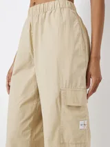 Pantalón cargo color beige de corte recto, con cintura elástica, bolsillos laterales y bolsillo cargo en la pierna.