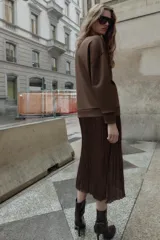 Vestido midi de manga larga, con parte superior tipo buzo de tejido liso color marrón oscuro y falda larga plisada de tejido satinado marrón oscuro.