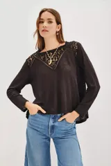 Remera de manga larga color negro, con detalle de encaje en la parte superior delantera y hombros. Presenta un corte holgado y fluido.