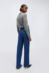 Jean de denim azul de tiro alto, con corte recto holgado, pliegues frontales y cierre con botón y cremallera.