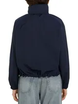 Cortavientos azul marino con cuello alto, cierre de cremallera, dos bolsillos con botones, detalles distintivos de Tommy Hilfiger y logo gráfico bordado en el pecho.