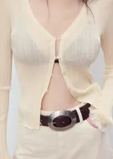 Cardigan de punto fino y semitransparente color beige, con escote en V, cierre frontal de botones y mangas largas con ribetes contrastantes en los puños.