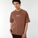 Remera marrón con mangas raglán y estampado con la leyenda "[NXT-K] NO LIMITS. NO HESITATIONS." en color blanco.