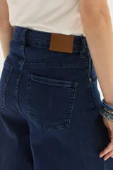 Jean de mezclilla azul oscuro, tiro alto, con pierna muy ancha (palazzo o wide leg) y costuras verticales marcadas en el frente.