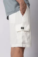 Bermuda cargo de lino y rayón color blanco, con bolsillos laterales tipo cargo, cintura elástica con cordón ajustable y calce relajado.