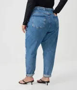 Pantalón mom jeans de tiro alto y corte holgado en caderas y piernas, con bolsillos, presillas para cinturón y cierre frontal con botón.