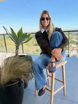 Saco de punto color chocolate con diseño de tejido acanalado, cuello redondo, cierre frontal con botones grandes y mangas globo con puños ajustados.