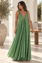 Vestido largo color dorado, confeccionado en tela semitransparente con diseño bordado floral y detalles de brillo. Presenta escote en V, tirantes finos ajustables con borlas en los hombros, y corte amplio y fluido con gran movimiento.