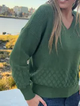 Sweater de punto verde oscuro, confeccionado en hilado de viscosa y lycra, con escote en V y diseño de rombos texturizados en la parte inferior y las mangas.