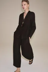 Camisa de lino color negro, de manga larga, con cuello solapa y cierre frontal con botones. Presenta un bolsillo de parche en el delantero.