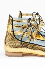 Botines dorados con estampado de escamas, con cordones negros y detalles calados.