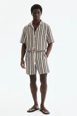Short de corte regular fit en tejido texturizado con mezcla de algodón, con diseño de rayas verticales en tonos marrón y crudo. Cuenta con cintura elástica ajustable con cordón y bolsillos laterales.