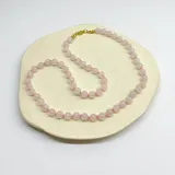 Collar de cuentas de cuarzo rosa de 6mm de diámetro, con separadores de hilo rosado y cierre de mosquetón de acero hipoalergénico con baño dorado.