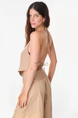 Top halter de tencel color beige con silueta asimétrica y diseño minimalista.