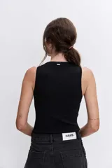 Pantalón de jean negro de corte recto y tiro alto, con detalle de botones metálicos plateados a lo largo de la costura lateral externa.