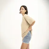 Remera marrón con estampado pequeño en el pecho que dice "We all grow" con una flor.