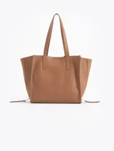 Bolso tipo tote de cuero color tostado con doble asa de hombro, detalles de hebillas metálicas en el frente y cierres laterales decorativos.