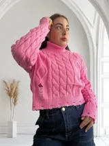 Sweater rosado de punto con cuello alto, mangas largas y diseño con roturas.