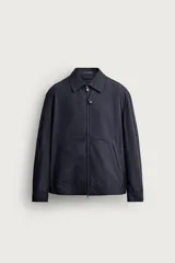 Cazadora regular fit de diseño ligero con patrón a cuadros en tonos azul marino y negro, confeccionada con mezcla de algodón y lino. Cuenta con cuello solapa, manga larga con puños abotonados, bolsillos de vivo en la cadera, detalles elásticos en los laterales del bajo y cierre frontal con cremallera de doble dirección.