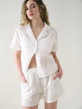 Short de broderie de algodón color blanco, con cintura elastizada, bolsillos laterales y botones decorativos frontales.