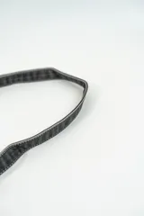 Cartera de hombro tipo baguette en color negro, con solapa frontal y correa ajustable con hebillas laterales.