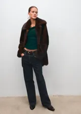 Top de manga corta color verde oscuro, confeccionado en tejido semitransparente con fruncidos laterales, cuello asimétrico y diseño entallado con forro interior.