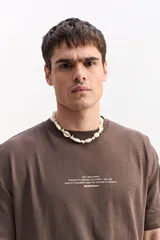 Remera oversize de manga corta color marrón con estampa pequeña en el pecho y estampa geométrica en la espalda.