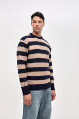 Buzo de punto con diseño de rayas horizontales en azul marino y beige, cuello redondo y puños acanalados. Presenta un pequeño bordado de estrella en la manga.