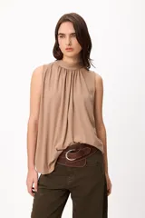 Blusa sin mangas color crema, con cuello alto fruncido y diseño holgado.