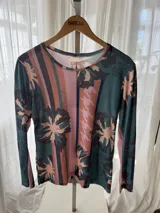 Remera de manga larga con cuello redondo, confeccionada en tejido de red semitransparente con estampado combinado de rayas, flores tropicales y detalles de animal print.